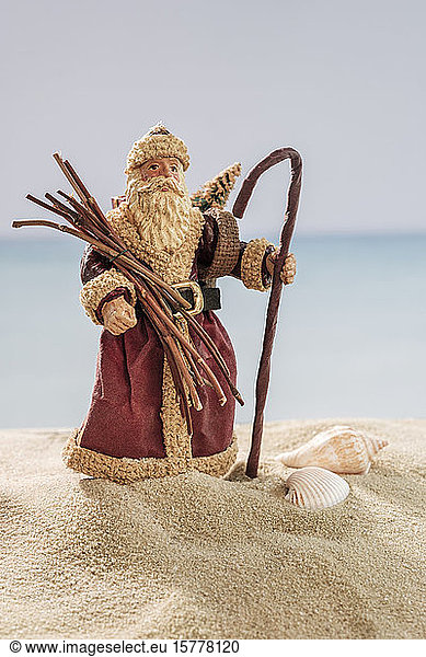 Weihnachtsmann-Ornament und Muscheln auf Sand