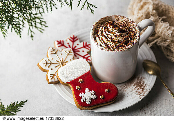 Weihnachtsplätzchen und eine Tasse mit schaumiger heißer Schokolade