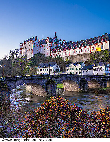 Weilburg Castle with river and old Lahn bridge under blue sky