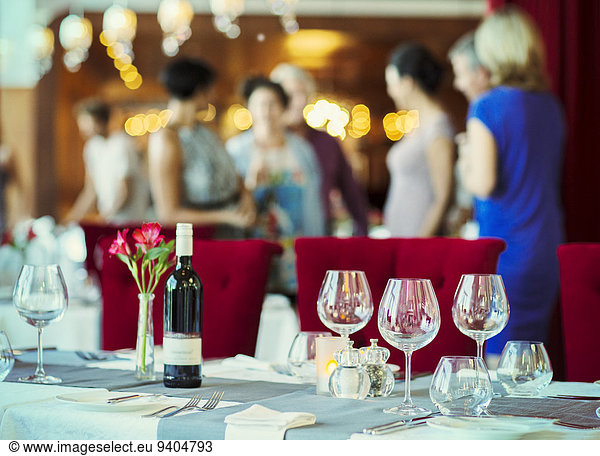 Weingläser und Flasche Rotwein auf dem Tisch im Restaurant  Menschen im Hintergrund