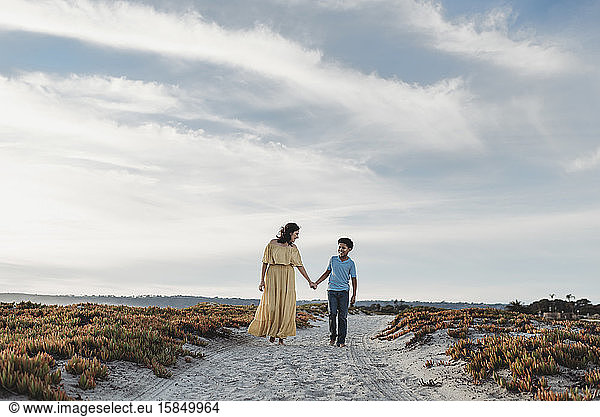 Weite Ansicht von Mutter und Sohn am Strand vor wolkenblauem Himmel