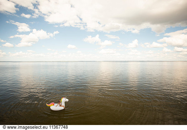 Weitwinkel-Distanzansicht einer jungen Frau  die auf einem aufblasbaren Einhorn im Meer sitzt  Santa Rosa Beach  Florida  USA
