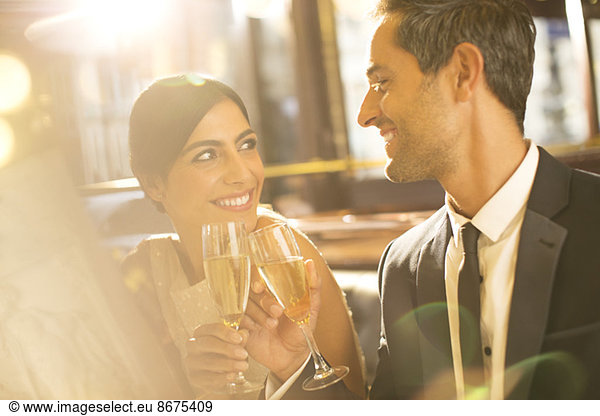 Well-dressed couple toasting champagne flutes in restaurant