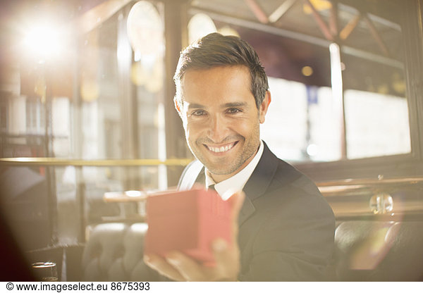 Well-dressed man holding jewelry box in restaurant