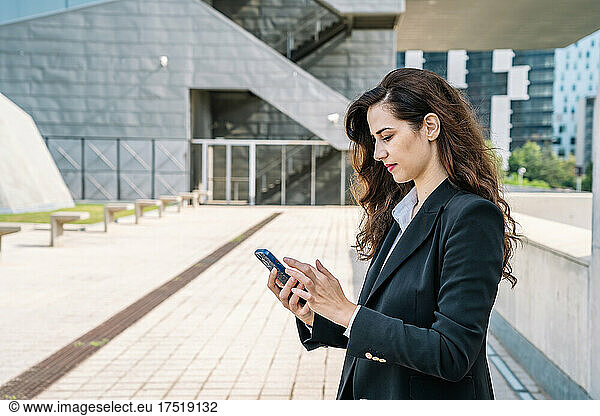 Well dressed young businesswoman messaging on smartphone
