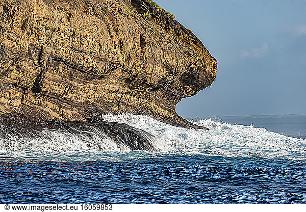 Wellenschnittkerbe am Molokini-Krater bei Maui (im Hintergrund)  Hawaii. Die Einkerbung ist das Produkt einer langfristigen Erosion durch Welleneinwirkung  wie hier auf dem vulkanischen Tuff  der den Molokini bildet; Hawaii  Vereinigte Staaten von Amerika