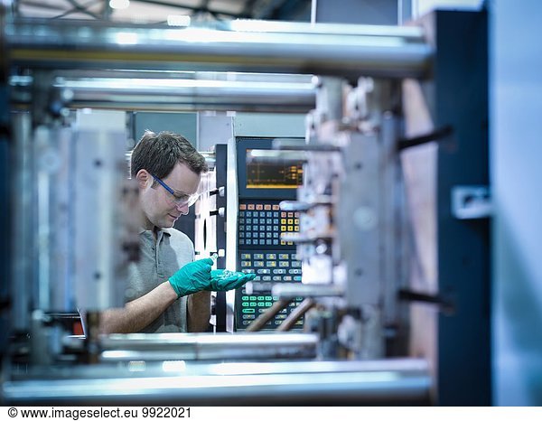 Werker inspiziert Teile von Kunststoffspritzgießmaschinen in der Kunststofffabrik