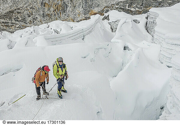 Westlicher Bergsteiger und Sherpa-Führer halten inmitten komplizierter Gletscherspalten inne