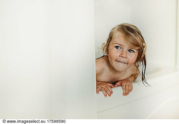 Wet girl peeking from shower curtain