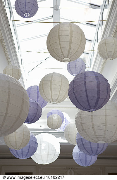 White and blue bamboo paper lanterns suspended from a ceiling.