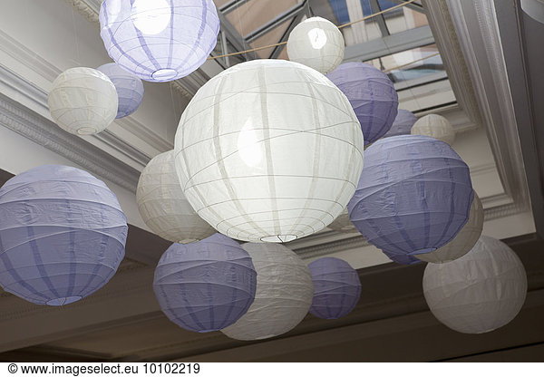 White and blue bamboo paper lanterns suspended from a ceiling.