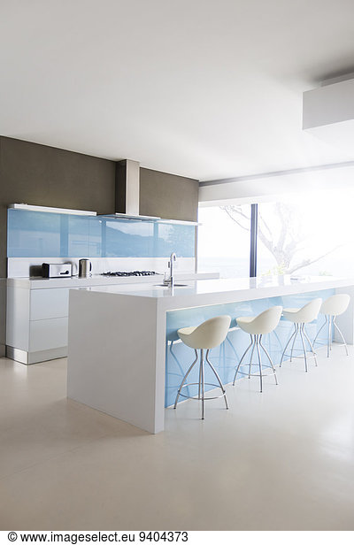 White and clean modern kitchen with stools at kitchen island