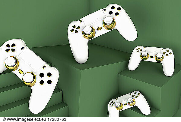 White and gold colored video game consoles on green backround