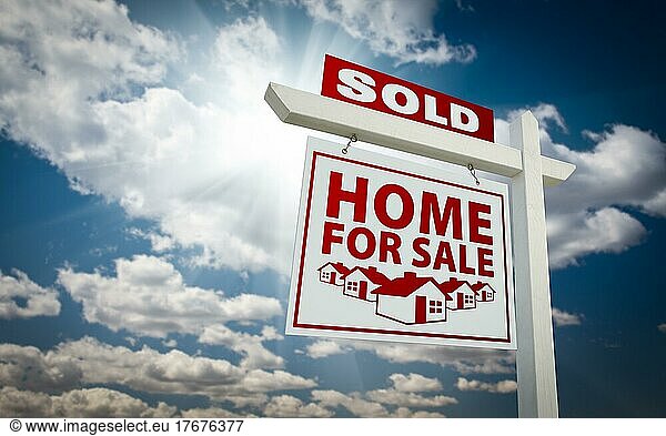 White and red sold home for sale real estate sign over beautiful clouds and blue sky