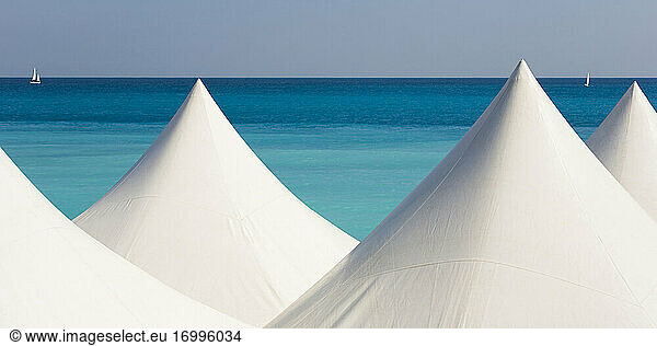 White beach tents against blue coastal water of Mediterranean Sea