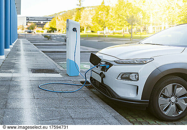 White car charging atÂ electric vehicle charging station