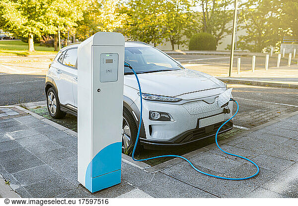 White car charging atÂ electric vehicle charging station