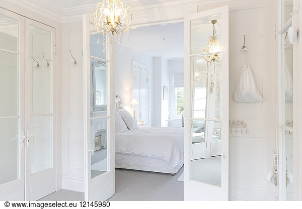 White  luxury home showcase interior bedroom with French doors and chandelier