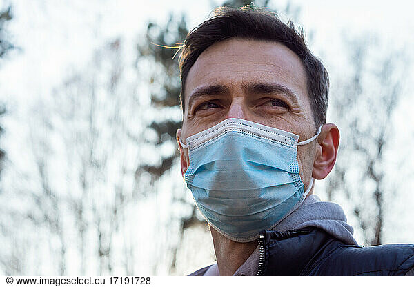 White middle-aged man wearing a medical mask outside in a sport outfit
