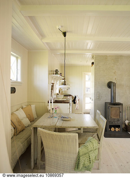 White panelled living room with dining table and wood burner