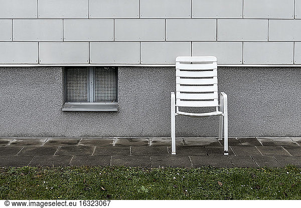 White plastic chair standing in front of a facade