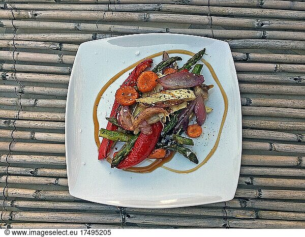 White plate Oven vegetables on straw mat with carrots  red pepper  green asparagus and onions