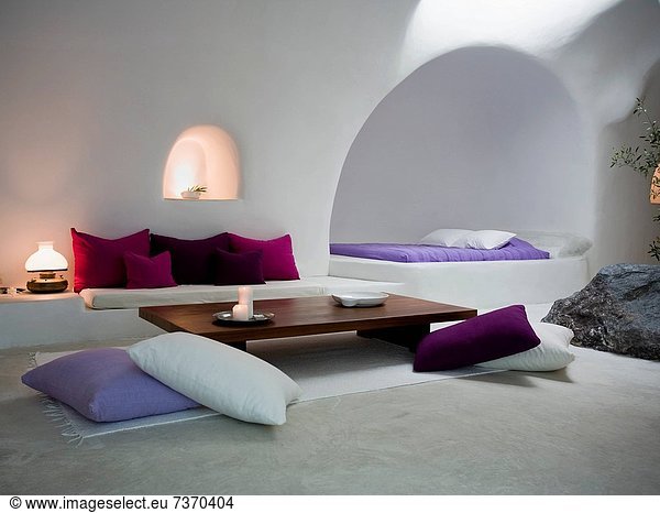 White room with throw pillows sofa and bed with rock inside