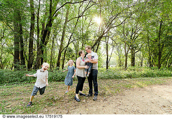 Wide angle view of a family of five playing together in the forest
