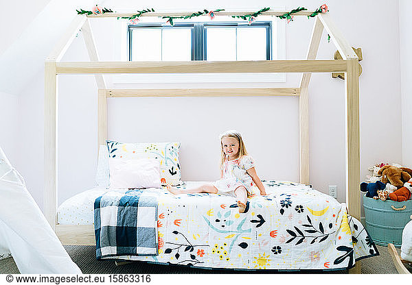 Wide portrait of a toddler girl smiling on her modern bed