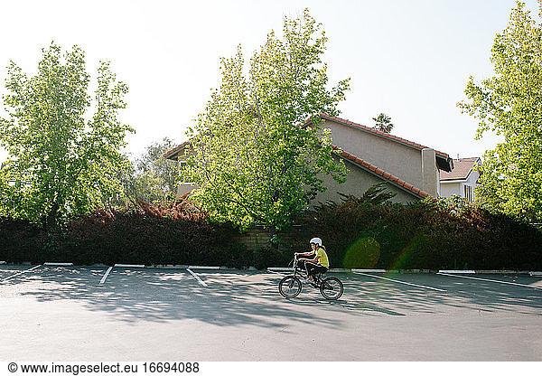 Wide shot profile of girl riding her bike in a parking lot
