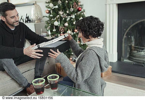 Wife opening Christmas gift from husband in living room