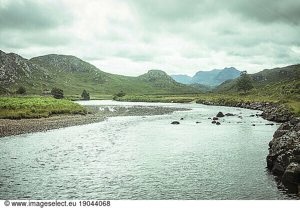 wild remote salmon river winds through mountains in scottish highlands