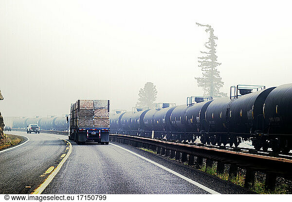 Wildfire smoke and highway traffic next to railway cars transporting oil