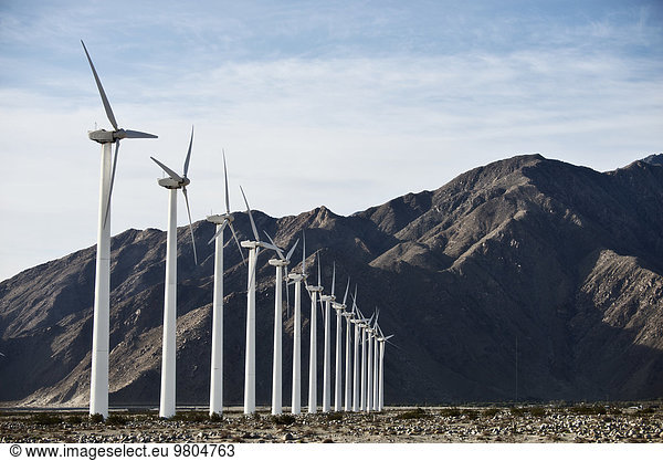 Wind power turbines in the landscape. A large number of turbine powers on a plain against a mountain backdrop.