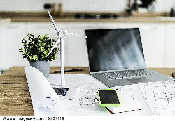 Wind turbine model  construction plan  cell phone and laptop on table in office