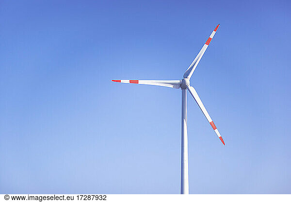 Wind turbine standing against clear blue sky