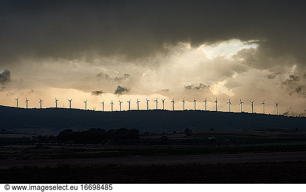 Wind turbines on a mountain top with a cloudy sky in the background