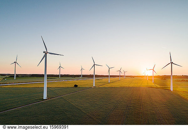 Wind turbines on grassy field against clear sky