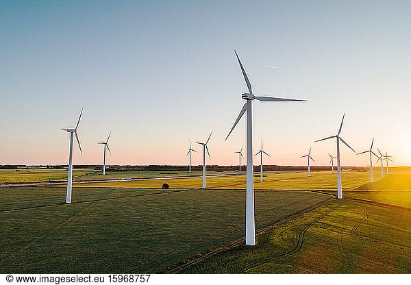 Wind turbines on grassy land against clear sky
