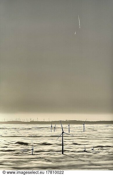 Wind turbines rising from cloud cover  wind power station  silhouettes at sunset  condensation trails in the sky  monochrome  text free space  Köterberg  Lügde  Weserbergland  North Rhine-Westphalia  Germany  Europe