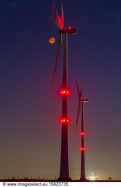 Wind wheels in front of blood moon at night