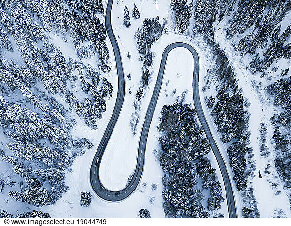 Winding road along snowy woods from above  Maloja Pass  Switzerland