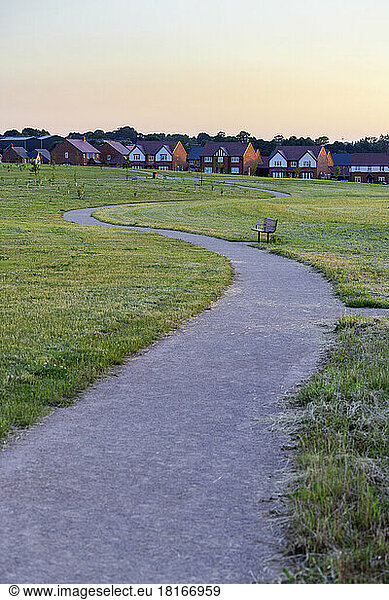 Winding road leading towards detached houses at sunset