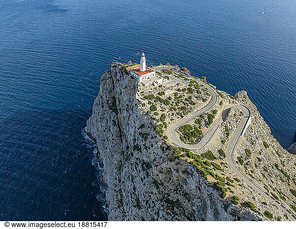 Winding road leading towards lighthouse on Cabo Formentor cliff amidst sea