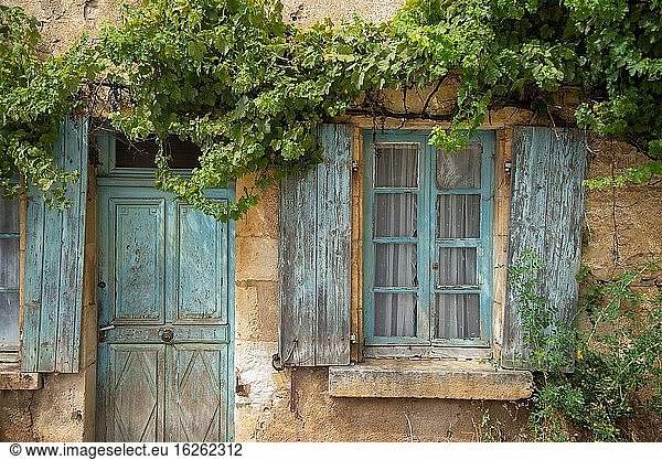 Window and door with old blue shutters in France