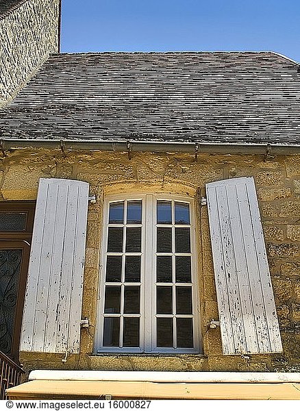 Window in stone wall with peeling shutters  Domme  Dordogne Department  Nouvelle Aquitaine  France.