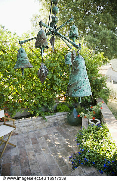 Windspiel oder Mobile mit Bronzeglocken über Gartenterrasse hängend.