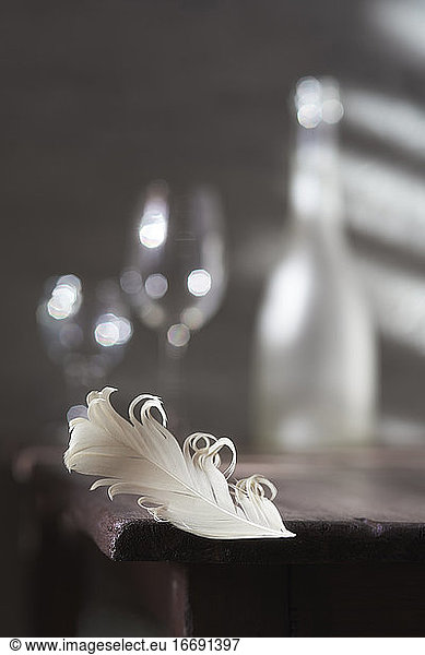 Wine glasses on the table and a beautiful white feather. Romantic date