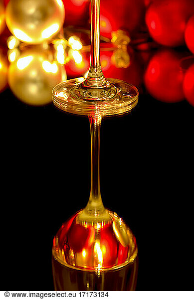 Wineglass reflected in glass surface with Christmas ornaments in background