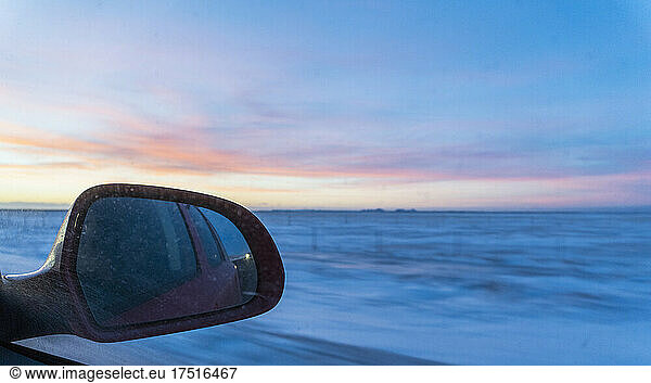 wing mirror of car driving through snowy landscape in Iceland